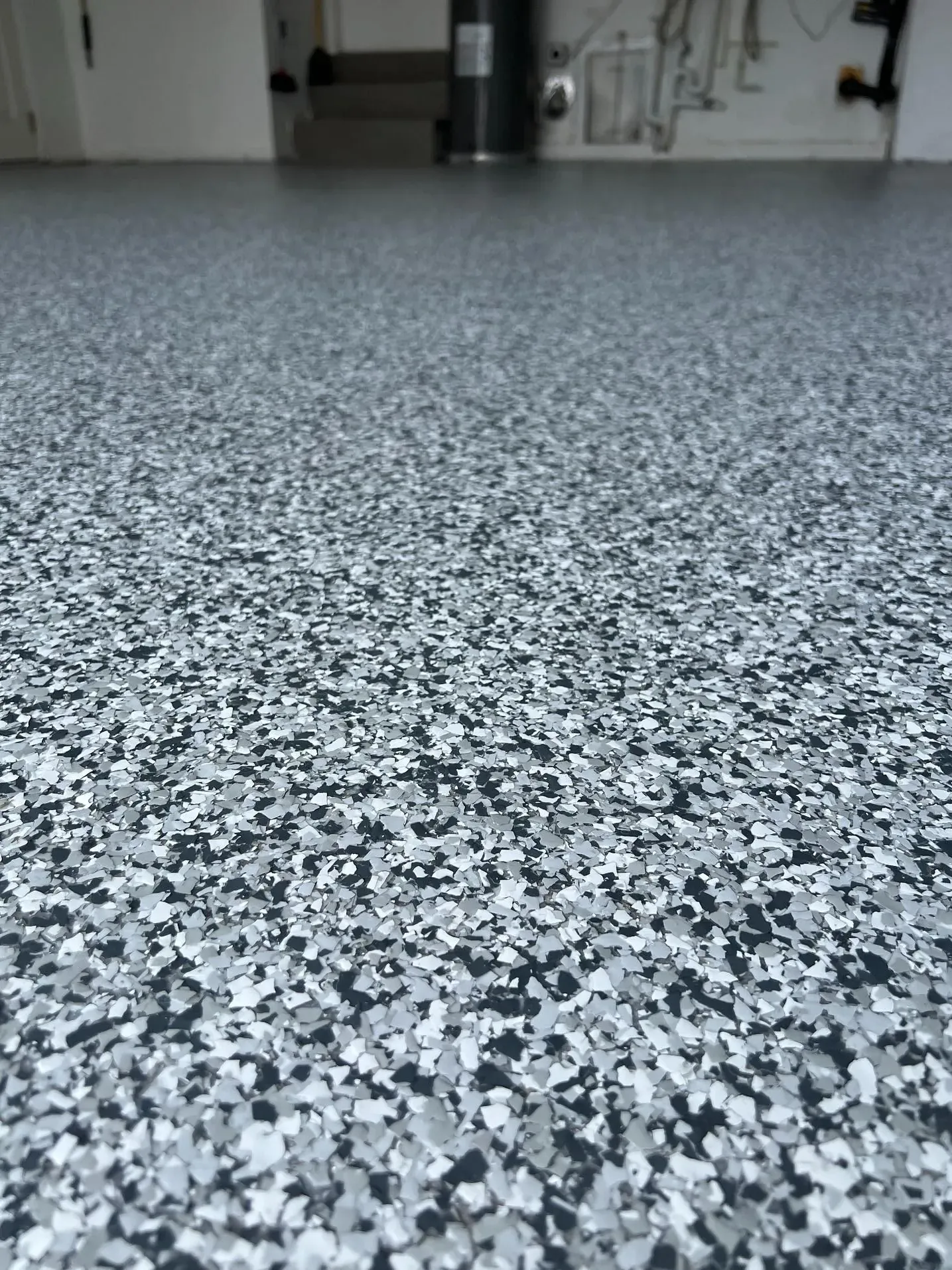 Residential garage floor coated with black, white and grey epoxy flakes, photographed at floor level