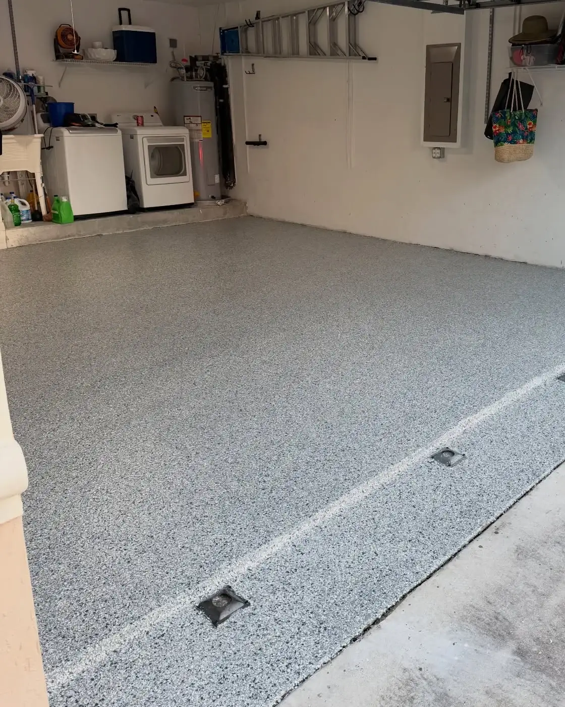 Two-car garage with a grey flake epoxy floor meeting the bare concrete driveway at the door line